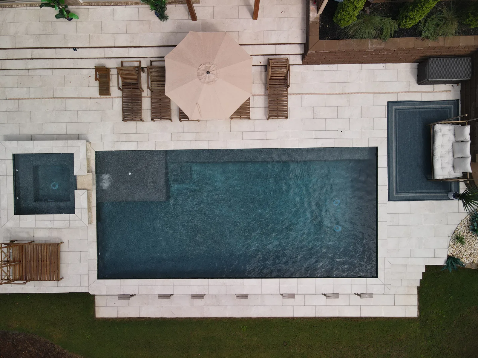 Drone view of a pool and patio that fill the whole backyard