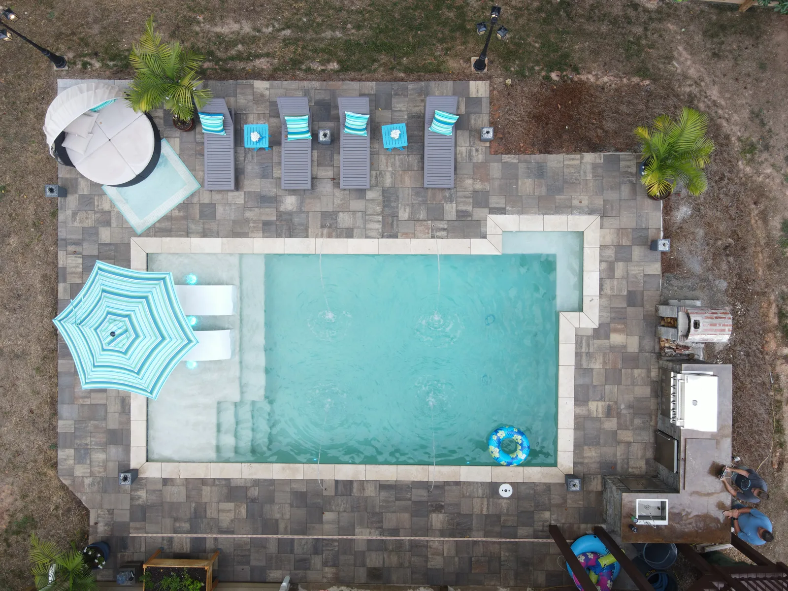 Drone view from above of a finished pool with an umbrella and paver patio