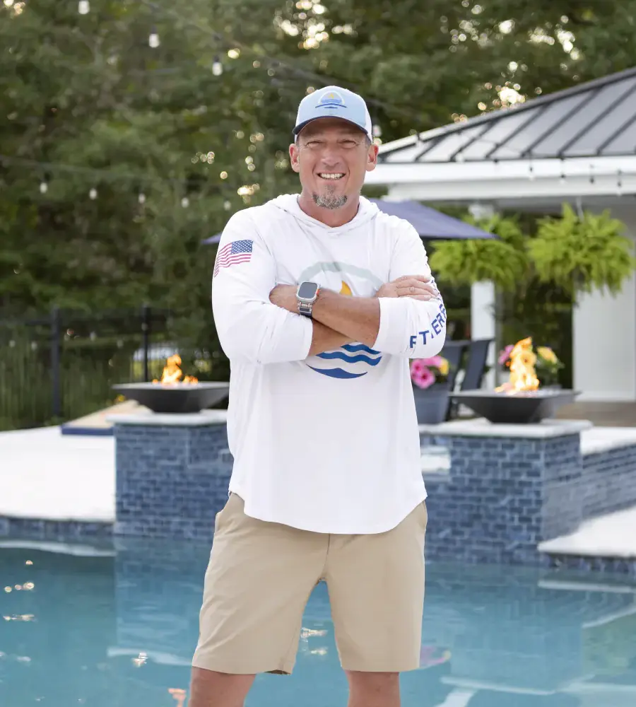 Scott Rutherford standing in front of a just-completed RutherfordMade pool with fire bowls and cabana