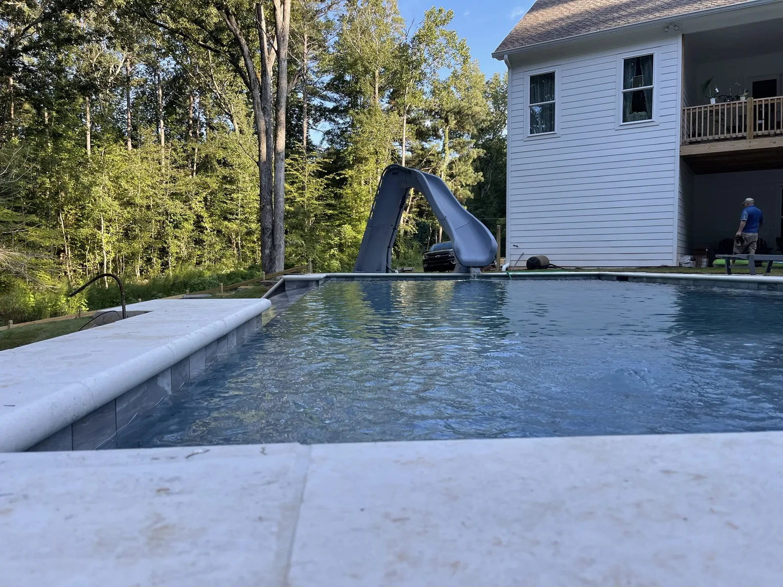 Pool with a slide behind a family home