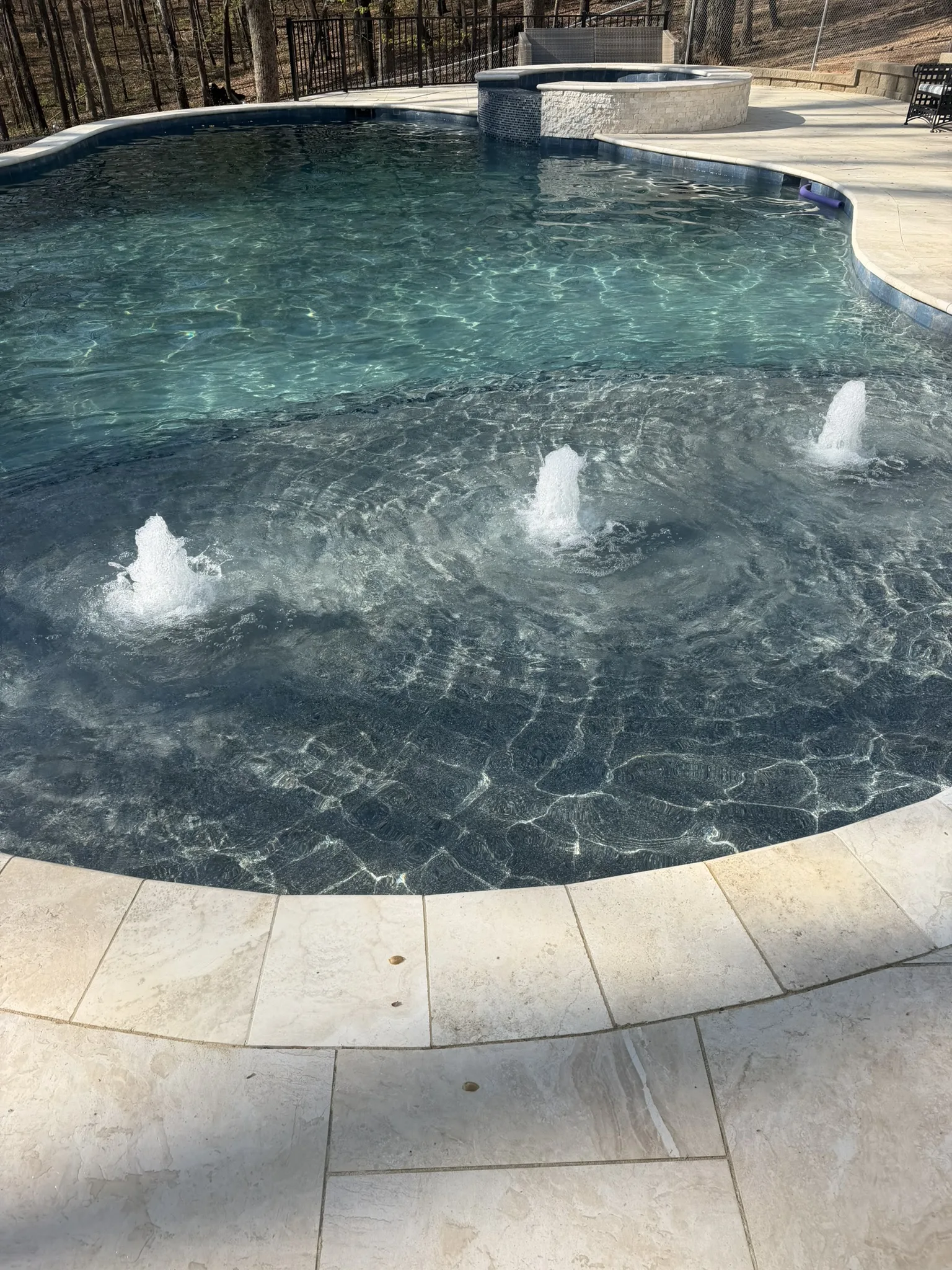 Pool with small fountains and a dark pebble finish
