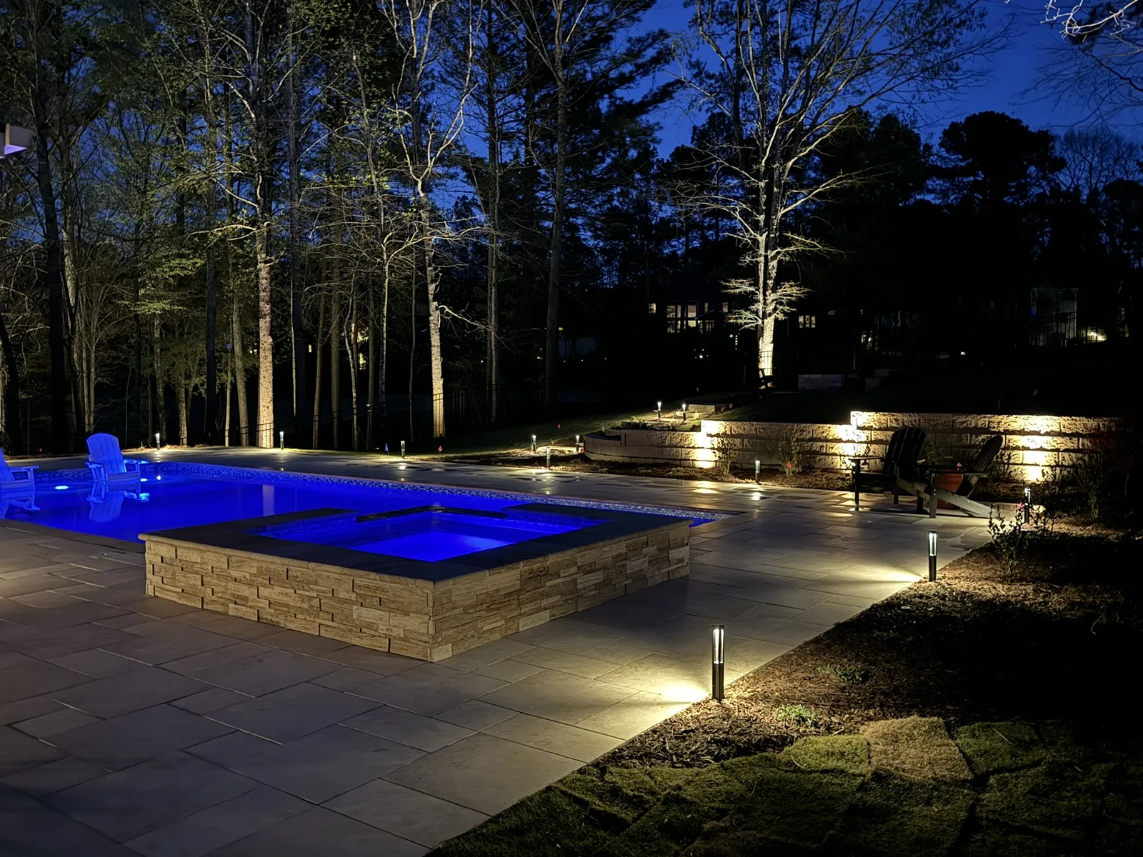 Pool lit blue at night with lights along the patio