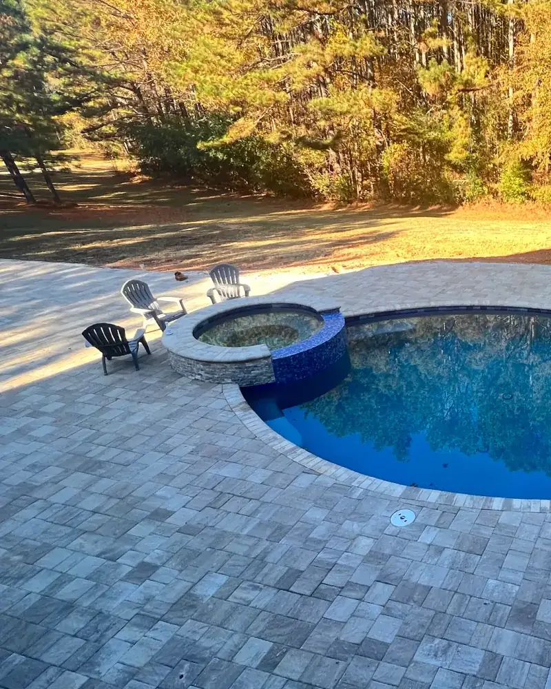 RutherfordMade pool, spa, and paver patio at dusk — designed for one-tap evening scenes with integrated lighting and automation